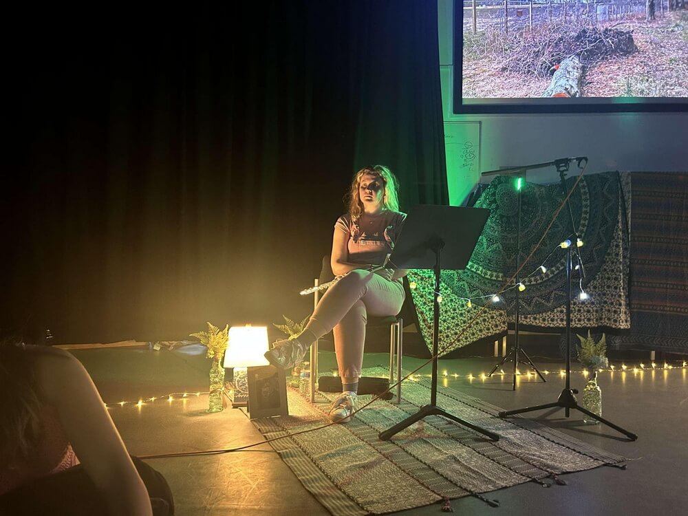 Kathryn seated with flute and score, projection of the site behind